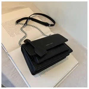 Detail view of a stylish black crocodile pattern women shoulder bag with chain strap and flap.