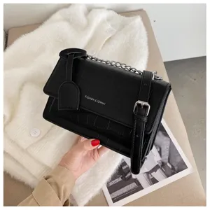 Detailed view of black crocodile pattern shoulder bag, featuring chain strap and metal buckle.