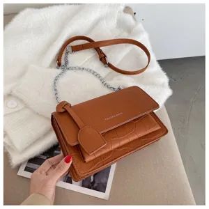 Brown crocodile pattern detail of stylish women shoulder bag with metal chain strap design.