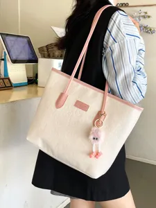 Detail view of large capacity color-contrast tote bag with embossed pattern and cute plush charm.