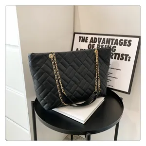 Detailed shot of a black quilted tote bag featuring gold chain straps in a modern scene.