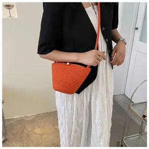 Orange woven bucket bag detail showing intricate straw texture and elegant pearl clasp design.