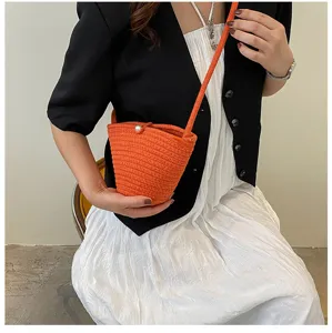Orange woven bucket bag detail, stylish small crossbody phone bag with pearl closure.