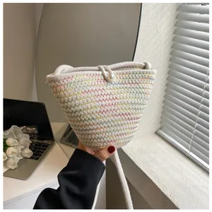 Detailed view of the white woven bucket bag with colorful zig-zag stitches and pearl button.