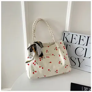 Vue détaillée du sac cabas en velours côtelé beige avec imprimé cerise et anse tressée.
