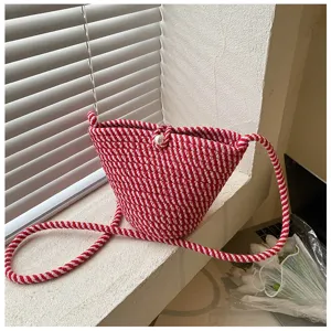 Detailed view of the red and white striped woven bucket bag showcasing texture and pearl clasp.