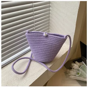 Purple woven bucket bag detail, small crossbody phone bag with pearl button closure.