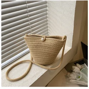 Chic woven bucket bag with pearl button closure, stylish single shoulder design detail shot.