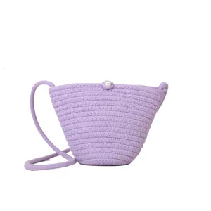 Purple woven crossbody bag with pearl closure detail showing texture and fine craftsmanship.