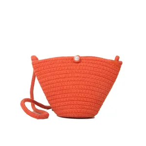 Orange woven crossbody bag detail showing the elegant pearl button closure and texture.