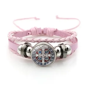 Pink braided leather bracelet detail featuring central St. Benedict medal charm and metal beads.