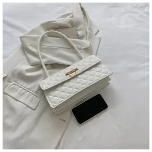 White quilted shoulder bag detail, elegant metal lock closure and handle, styled flat lay scene.
