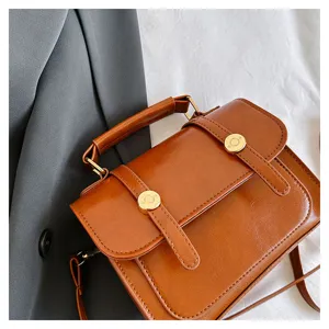 Détail en gros plan du cartable vintage en cuir PU marron avec boucle métallique et poignée.