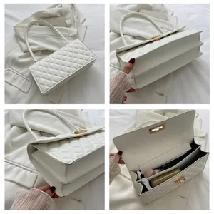 White quilted underarm bag detail, showcasing interior compartments, metal lock and strap.