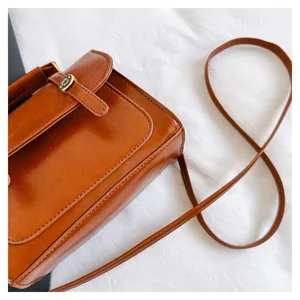 Gros plan détail du sac bandoulière en cuir PU marron, sac style collège élégant avec fermoir métal.