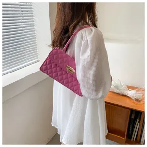 Close-up view of a chic pink quilted underarm bag with stylish metal lock closure.