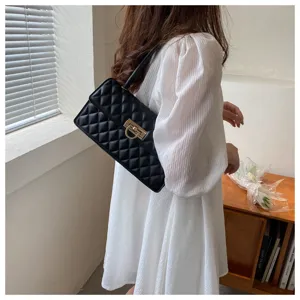 Close-up of black quilted underarm bag featuring chic gold lock and elegant diamond pattern.