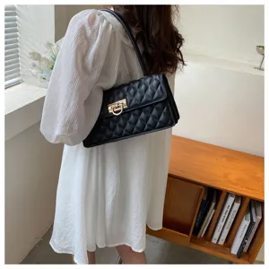 Detailed view of a black quilted shoulder bag with metal lock, lifestyle indoor setting.