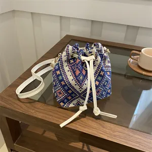 Detailed close-up of a woven geometric bucket bag with white leather drawstrings and strap.