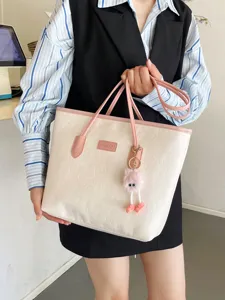 Detailed beige pink contrast tote bag with embossed patterns and cute plush eye pendant.