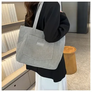 Detail shot of a grey corduroy tote bag with large capacity, shoulder bag style.