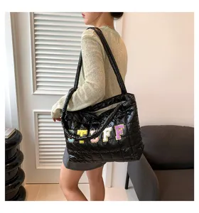Close-up detail of black quilted down cotton tote bag featuring colorful letter embroidery.