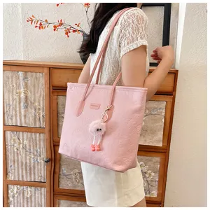 Stylish pink tote bag for women with embossed design and cute furry charm, perfect for daily commute.