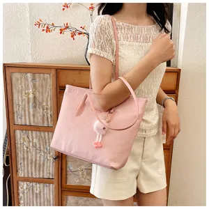 Detailed view of the pink debossed tote bag with cute plush pendant, stylish shoulder design.