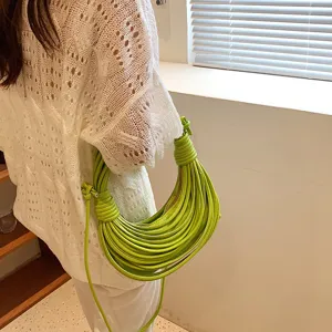 Detailed view of the bright green knotted noodle shoulder bag in a clean indoor setting.