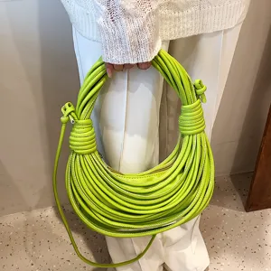 Detail view of bright green knotted handbag, showcasing unique noodle strap design and texture.