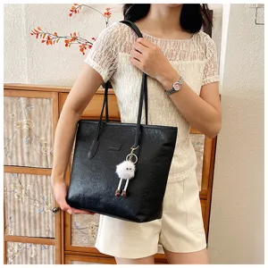 Detail shot of the black embossed tote bag worn by model, showing texture and fuzzy keychain.