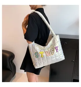 Detail view of white quilted puffer shoulder bag with colorful embroidered letters, stylish.