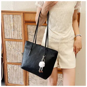 Detailed view of black embossed tote bag, large capacity shoulder bag with cute fluffy pendant.