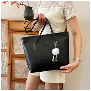 Black embossed tote bag for women, large capacity shoulder handbag with plush pendant.
