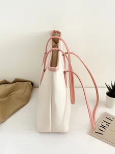 Detail shot of a minimalist cream white tote bag featuring contrast pink straps and embossed texture.