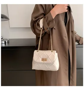 Detail view of stylish white quilted shoulder bag with gold chain strap and elegant clasp.