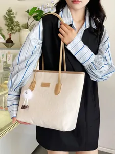 Detailed view of the elegant beige tote bag with embossed pattern, double handles and fluffy charm.