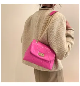 Detail shot of a bright pink quilted shoulder bag featuring a stylish gold chain strap.