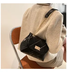 Detail view of black quilted leather shoulder bag with golden chain strap and chic lock.