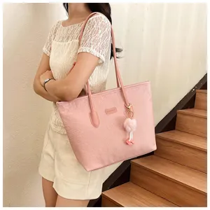 Pink tote bag detail showing embossed pattern and cute pom-pom keychain accessory.