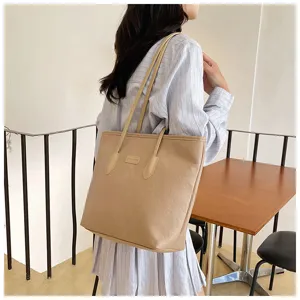 Detailed view of a stylish beige tote bag with debossed pattern carried by a model.