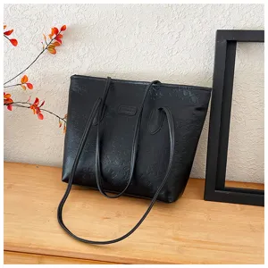 Black embossed tote bag detail shot showing PU leather texture and dual shoulder straps.