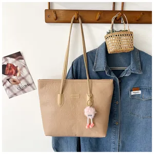 Beige PU leather tote bag with embossed patterns and cute fluffy charm for women commuting.