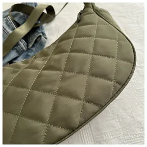 Close-up detail of olive green quilted nylon dumpling shoulder bag with wide strap texture view.
