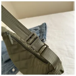 Detail view of green nylon dumpling crossbody bag strap, stylish quilted shoulder bag.