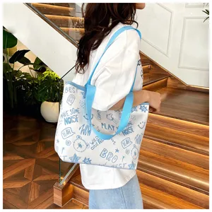 Detail view of casual canvas bag showing blue graffiti print and blue shoulder strap.