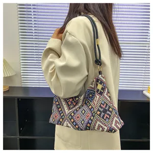 Detailed shot of ethnic geometric woven shoulder bag with black strap and metal ring.