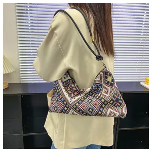 Detailed view of women's ethnic pattern shoulder bag with colorful woven fabric and black strap.