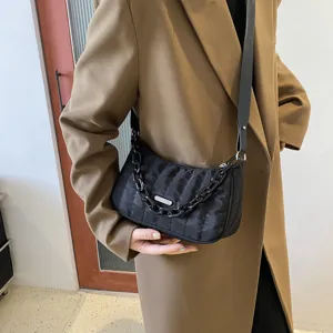 Black quilted nylon shoulder bag featuring chunky chain strap and metal accent plate.