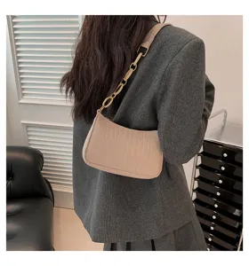 Borsa a spalla beige con trama coccodrillo e spessa catena dorata per donne alla moda.